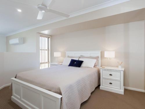 a white bedroom with a white bed and a window at Walk on Birubi 1 Pet Friendly WI-FI Boat Parking and Water Views in Anna Bay