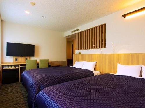 a hotel room with two beds and a flat screen tv at Komagane Premont Hotel in Komagane