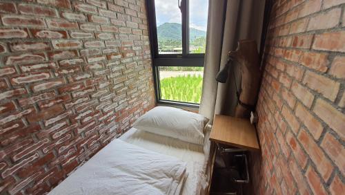 a room with a brick wall with a bed and a window at 缽割貓點點 青旅 DianDian hostel in Puli