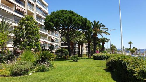 a park with trees and bushes in front of a building at Garden and beach sea view apartment Cannes in Cannes