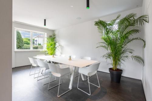 a dining room with a white table and chairs and a plant at GoTì Hotel in Nago-Torbole