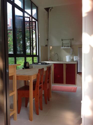a kitchen with a wooden table and some chairs at Gaze Studio: Modern Spacious Jungle Stay in Pantai Cenang