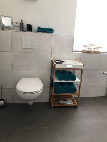 a bathroom with a toilet and a shelf with towels at Ferienwohnung Kleine Auszeit in Maring-Noviand