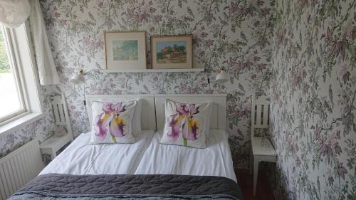 a bedroom with a bed with pink floral wallpaper at STF Vickleby Bo Pensionat in Färjestaden