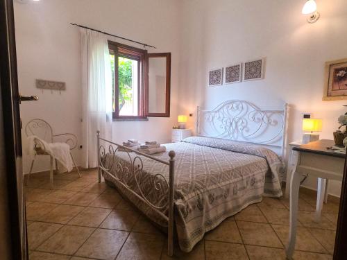 a bedroom with a bed and a table and a window at Villa Sweet Simius in Villasimius