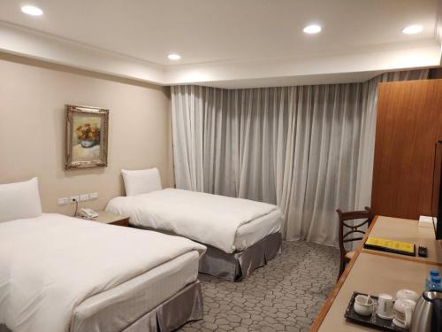 埔里にあるアポロ ホテルのベッド2台とデスクが備わるホテルルームです。