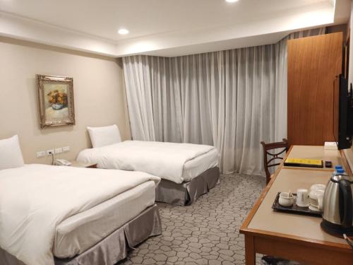 埔里にあるアポロ ホテルのベッド2台とデスクが備わるホテルルームです。