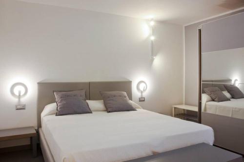 a white bedroom with two beds and two lamps at Via Mare in Ginosa Marina