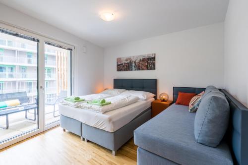sypialnia z łóżkiem, kanapą i oknem w obiekcie FeelGood Apartments GreenLiving | contactless check-in w Wiedniu