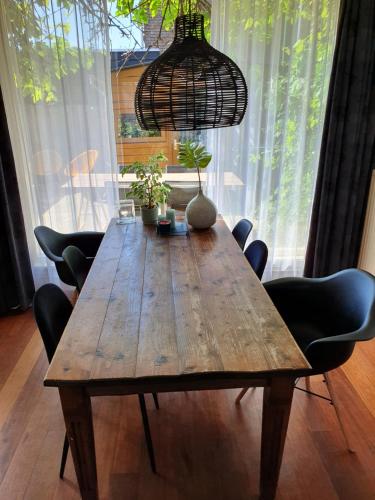 einem Holztisch mit Stühlen und einer Hängeleuchte in der Unterkunft Single family home in Hillegersberg - Schiebroek in Rotterdam