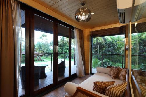 a living room with a couch and large windows at Maliekal Heritance Cherai Beach Cochin in Cherai Beach