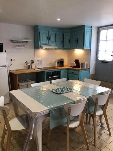 une cuisine avec des armoires bleues et une table et des chaises dans l'établissement L'HISTORIQUE - Maison rénovée dans le centre-ville de Bayeux, à Bayeux
