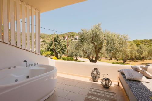 a bathroom with a tub and a balcony with trees at Skiathos Avaton Hotel, Philian Hotels & Resorts in Skiathos Town