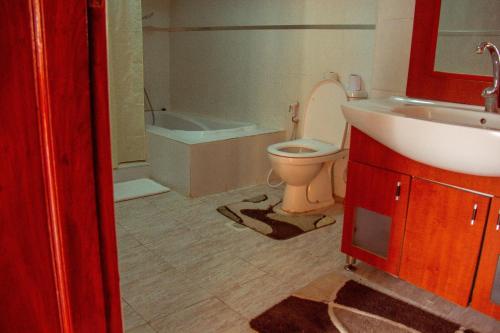 a bathroom with a toilet and a sink and a tub at New Charity Hotel International in Arusha