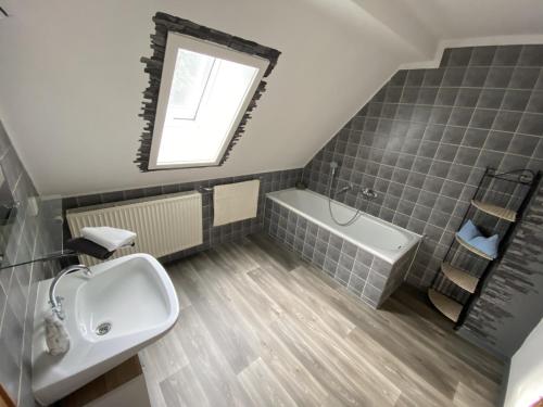 a bathroom with a sink and a tub and a mirror at Fewo Lindenhof in Hatzfeld