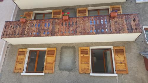 un edificio con persianas de madera y balcón en Chambre à louer à la nuitée, en Lanslebourg-Mont-Cenis