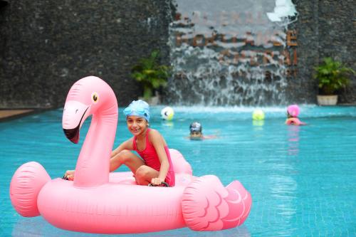 a girl sitting on an inflatable flamingo in a pool at Maliekal Heritance Cherai Beach Cochin in Cherai Beach
