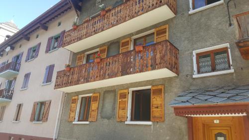 un edificio con persianas de madera y balcón en Chambre à louer à la nuitée, en Lanslebourg-Mont-Cenis