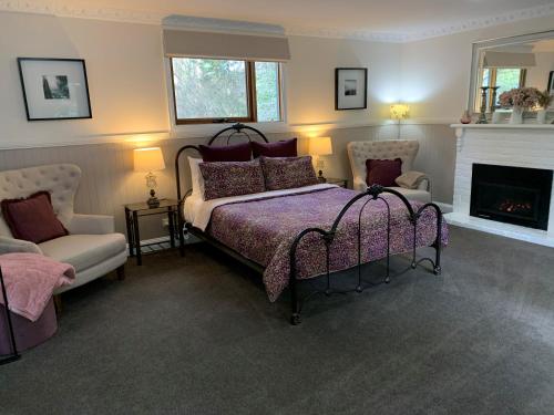 a bedroom with a bed and two chairs and a fireplace at Clarendon Cottages in Sassafras