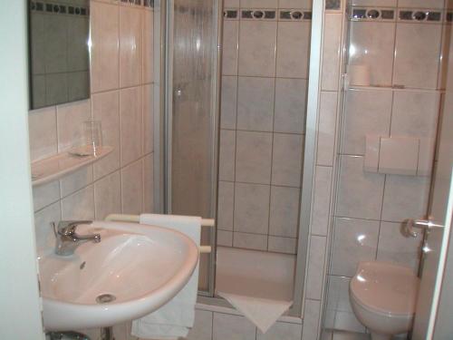 ein Bad mit einem Waschbecken, einer Dusche und einem WC in der Unterkunft Hotel Am Stadthaus Garni in Lohmar