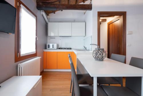 a kitchen with a white table and a kitchen with orange cabinets at Design Palace Apartment by Wonderful Italy in Venice