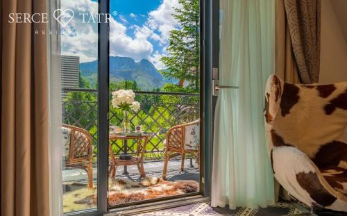 a dog standing in front of a sliding glass door at Serce Tatr Residence Zakopane - blisko Krupówek in Zakopane