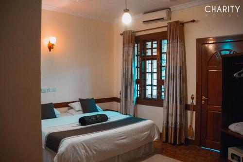 een slaapkamer met een bed met blauwe lakens en een raam bij New Charity Hotel International in Arusha