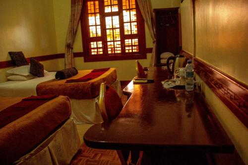 a room with two beds and a desk and a window at New Charity Hotel International in Arusha