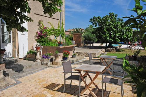 un patio con 2 mesas, sillas y flores en Maison Matisse, en Saint-Nazaire-dʼAude