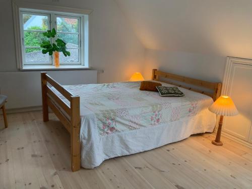 a bedroom with a bed and two lamps and a window at Lohalshygge in Tranekær