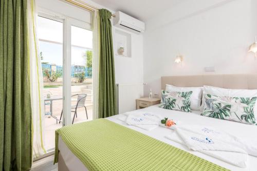 Schlafzimmer mit einem Bett mit grünen Vorhängen und einem Fenster in der Unterkunft Stratos Deluxe Apartments in Skala Potamias