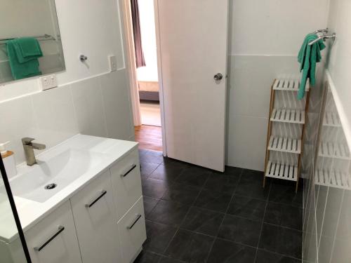 a bathroom with a white sink and a mirror at Airlie Getaway Unit 1 in Cannonvale