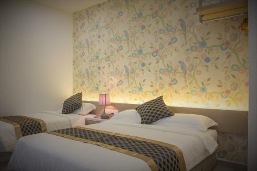 two beds in a room with flowers on the wall at Secret Garden Warni Villa (MUAR) in Muar