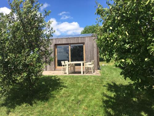 a wooden cabin with a table and chairs in the grass at De Kleine Mote in Heuvelland