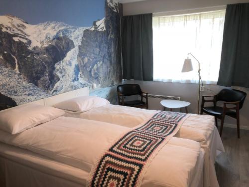 a bedroom with a bed with a mountain mural on the wall at Eikum Hotel in Hafslo