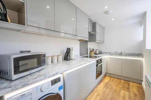a kitchen with white cabinets and a microwave at Knavesmire Studio in York