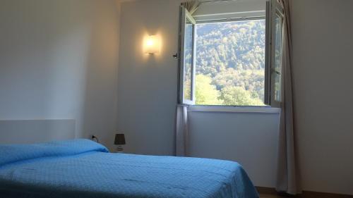 a bedroom with a blue bed and a window at Casa di Elisa in Gardone Riviera