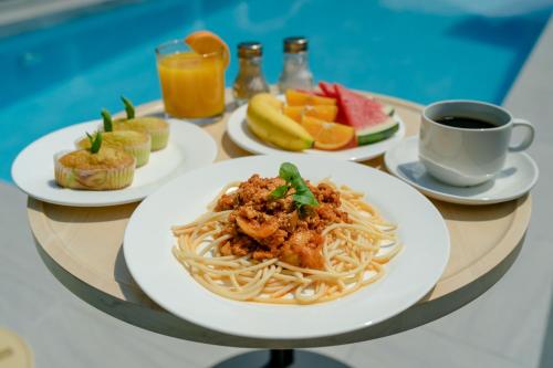een tafel met borden pasta en een kop koffie bij Cenang Rooms With Pool by Virgo Star Resort in Pantai Cenang