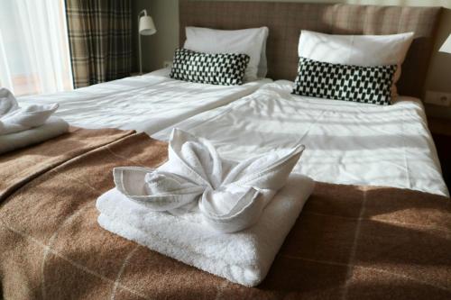 a bed with towels and a flower on it at Palanga Visit Apartments and SPA in Palanga