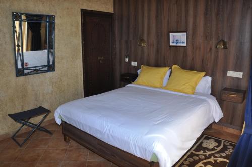 Schlafzimmer mit einem Bett mit weißer Bettwäsche und gelben Kissen in der Unterkunft Gite Nadia in Casablanca