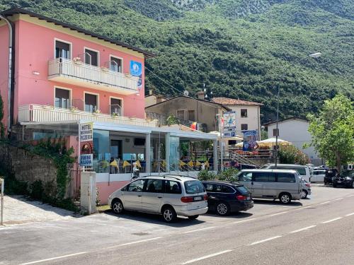 a street with cars parked in front of a pink building at Hotel Vela Azzurra in Malcesine