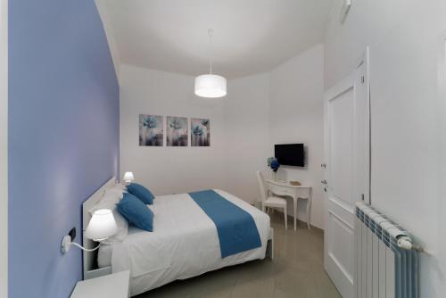 una camera da letto blu e bianca con letto e scrivania di Suite & Luxury Rooms Palazzo Diomede Carafa a Napoli