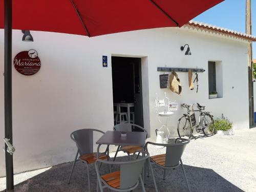 a table and chairs under an umbrella in front of a building at CASA AVÓ CATARINA Mesquita, turismo na aldeia in Espírito Santo