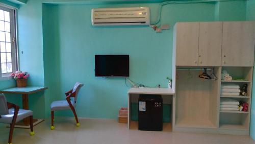 una camera con parete blu, scrivania e riscaldamento di Vineyard Guest House a Città di Taitung