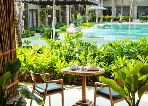 a table and chairs next to a swimming pool at M Village Phu Quoc in Phu Quoc