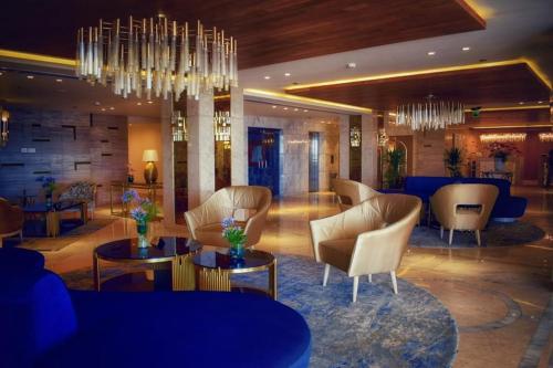 a lobby with chairs and tables and a chandelier at Romance Alexandria Hotel in Alexandria