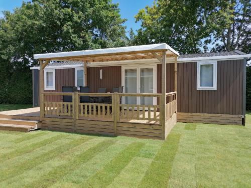a cabin with a deck and a gazebo at Vakantiepark duinzicht in Koudekerke