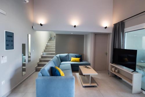a living room with a blue couch and a staircase at ANATOLI VILLAS in Nikiana