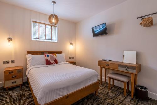 a bedroom with a bed and a desk and a television at Palace Hill Hotel in Scarborough