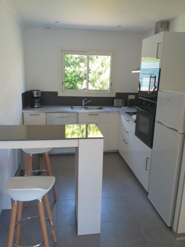 - une cuisine blanche avec un comptoir et des tabourets dans l'établissement Maison de vacances, à Laurac-en-Vivarais